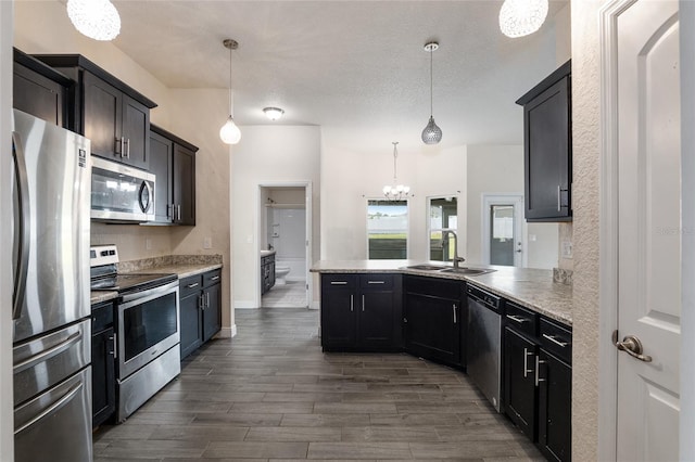 10910 SW 41st Ave, Ocala, FL 34476 - kitchen with appliances with stainless steel finishes, a sink, a peninsula, a chandelier, and dark wood-style floors