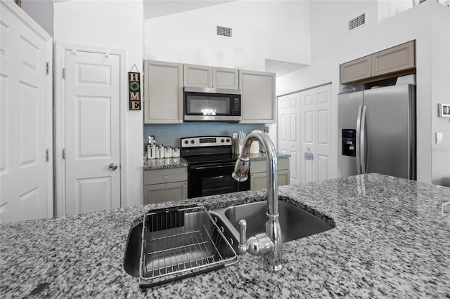 15324 SW 40th Place Rd, Ocala, FL 34481 - kitchen with appliances with stainless steel finishes, gray cabinets, light stone countertops, and a towering ceiling