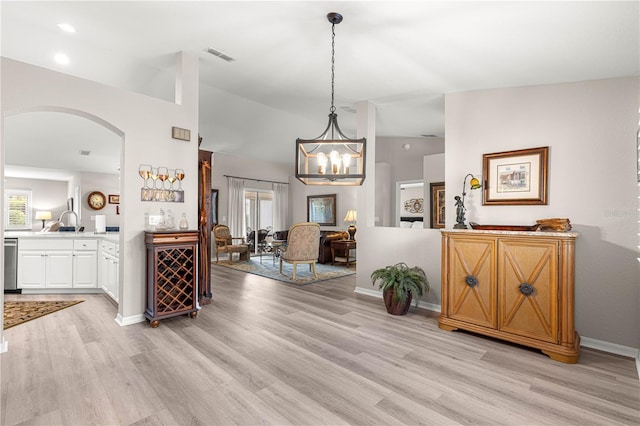 13715 SE 88th Ct, Summerfield, FL 34491 - dining room featuring arched walkways, lofted ceiling, light wood finished floors, baseboards, and a chandelier