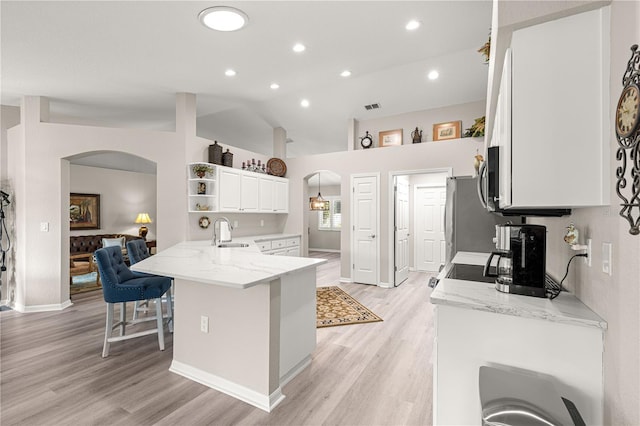 13715 SE 88th Ct, Summerfield, FL 34491 - kitchen featuring arched walkways, a sink, open shelves, light wood-style floors, and lofted ceiling