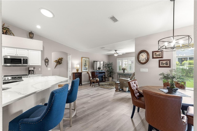 13715 SE 88th Ct, Summerfield, FL 34491 - dining space with arched walkways, light wood-style flooring, a chandelier, vaulted ceiling, and recessed lighting