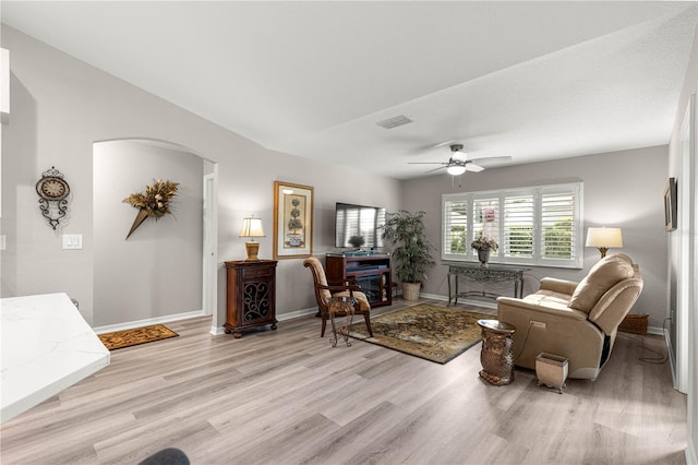13715 SE 88th Ct, Summerfield, FL 34491 - living room featuring arched walkways, light wood finished floors, baseboards, and a ceiling fan