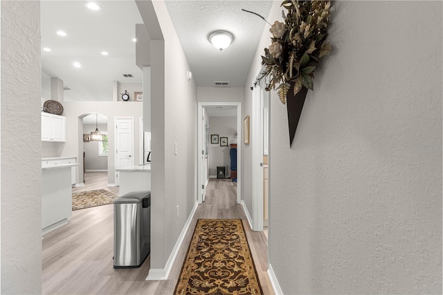 13715 SE 88th Ct, Summerfield, FL 34491 - corridor featuring arched walkways, light wood-style floors, a textured wall, recessed lighting, and a sink