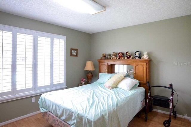 6190 SW 84th Pl, Ocala, FL 34476 - bedroom featuring a textured ceiling, wood finished floors, and baseboards