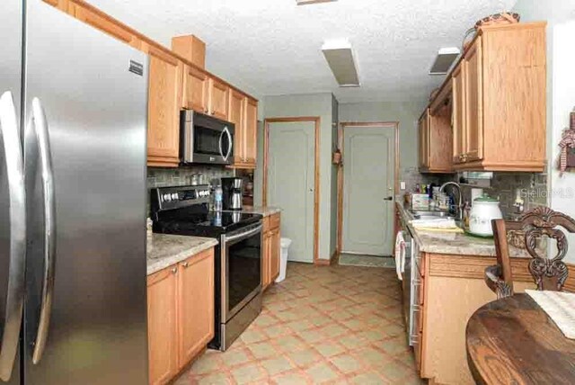 6190 SW 84th Pl, Ocala, FL 34476 - kitchen featuring stainless steel appliances, a sink, light floors, backsplash, and a textured ceiling
