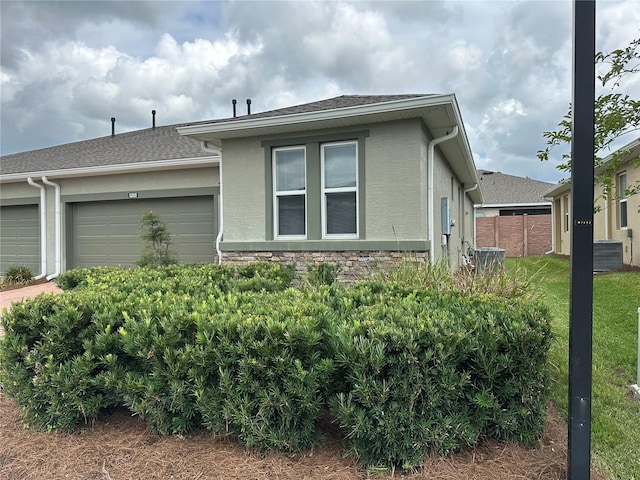 5255 NW 33rd Pl, Ocala, FL 34482 - view of side of property with a garage, stucco siding, central AC, and stone siding
