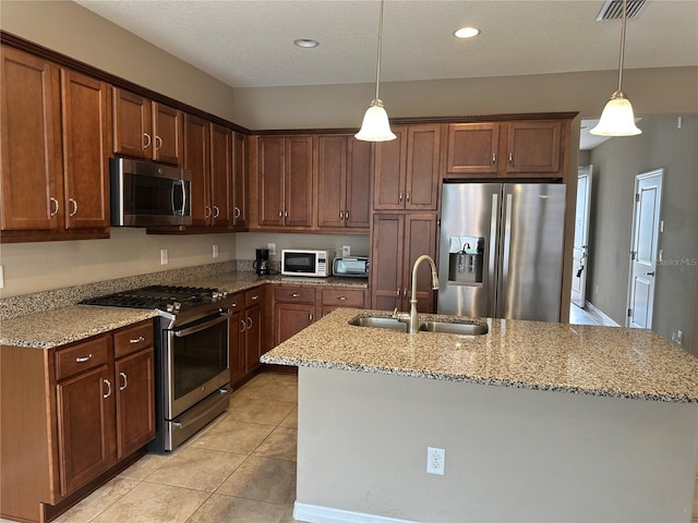 5255 NW 33rd Pl, Ocala, FL 34482 - kitchen with appliances with stainless steel finishes, a sink, a kitchen island with sink, light stone counters, and hanging light fixtures