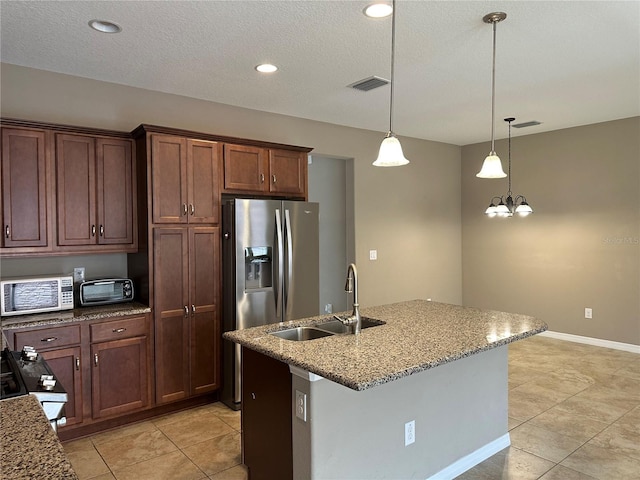 5255 NW 33rd Pl, Ocala, FL 34482 - kitchen featuring white microwave, a sink, decorative light fixtures, light stone counters, and a kitchen island with sink