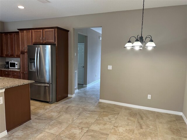 5255 NW 33rd Pl, Ocala, FL 34482 - kitchen featuring stainless steel refrigerator with ice dispenser, white microwave, light stone counters, baseboards, and a chandelier