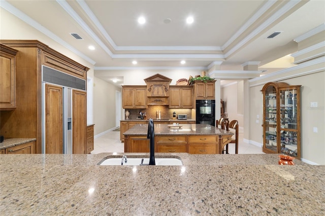 7915 SE 12th Cir, Ocala, FL 34480 - kitchen with a sink, light stone counters, brown cabinetry, tasteful backsplash, and an island with sink