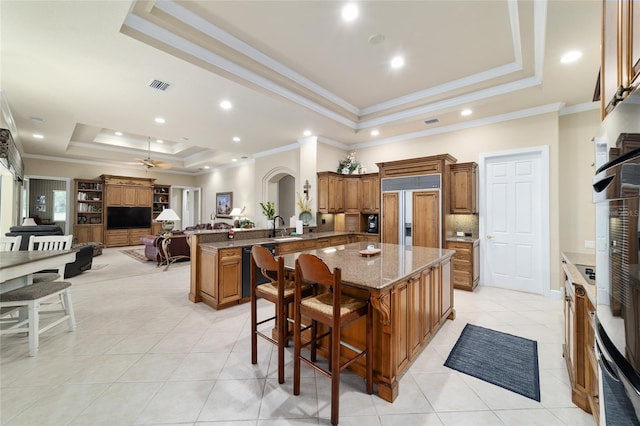 7915 SE 12th Cir, Ocala, FL 34480 - kitchen with a raised ceiling, paneled refrigerator, brown cabinetry, a peninsula, and light tile patterned floors