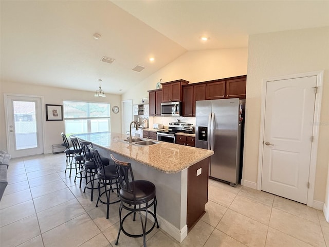 186 NW 44th St, Ocala, FL 34475 - kitchen featuring stainless steel appliances, an island with sink, a breakfast bar area, vaulted ceiling, and light tile patterned flooring