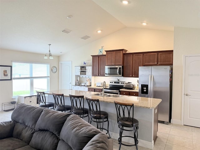 186 NW 44th St, Ocala, FL 34475 - kitchen featuring stainless steel appliances, open floor plan, a kitchen breakfast bar, lofted ceiling, and tasteful backsplash