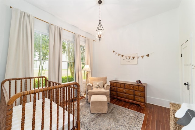 828 SE 3rd St, Ocala, FL 34471 - bedroom with baseboards, wood-type flooring, a crib, and a chandelier