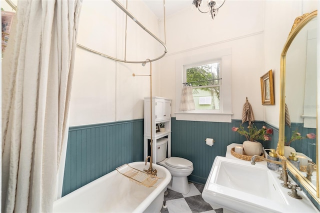 828 SE 3rd St, Ocala, FL 34471 - bathroom featuring wainscoting, a freestanding bath, a sink, toilet, and a shower with shower curtain