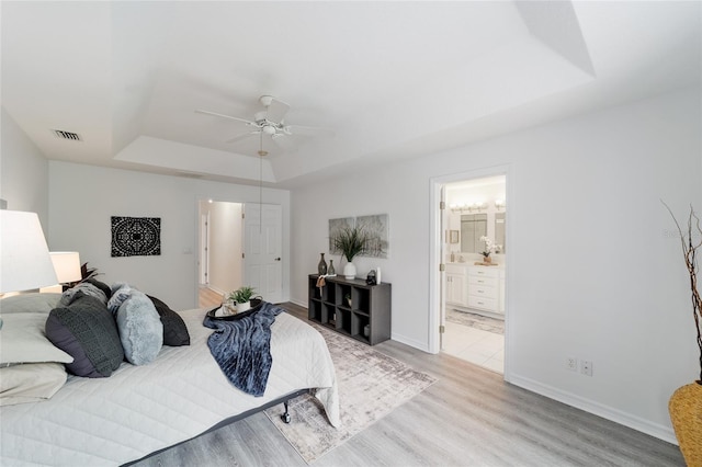 2644 SW 20th Cir, Ocala, FL 34471 - bedroom with a raised ceiling, light wood-style flooring, ensuite bath, baseboards, and a ceiling fan