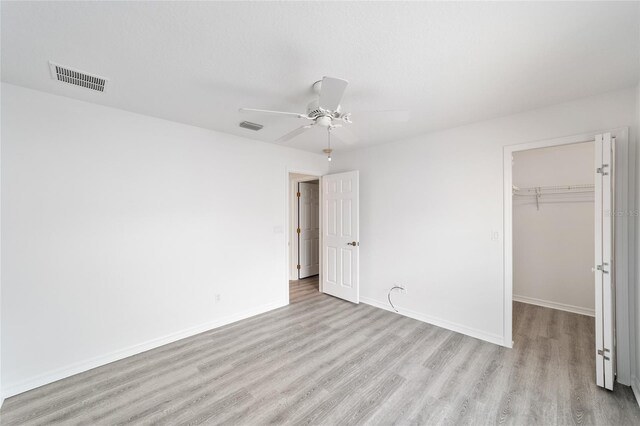 2644 SW 20th Cir, Ocala, FL 34471 - unfurnished bedroom with light wood-type flooring, a closet, a spacious closet, baseboards, and ceiling fan