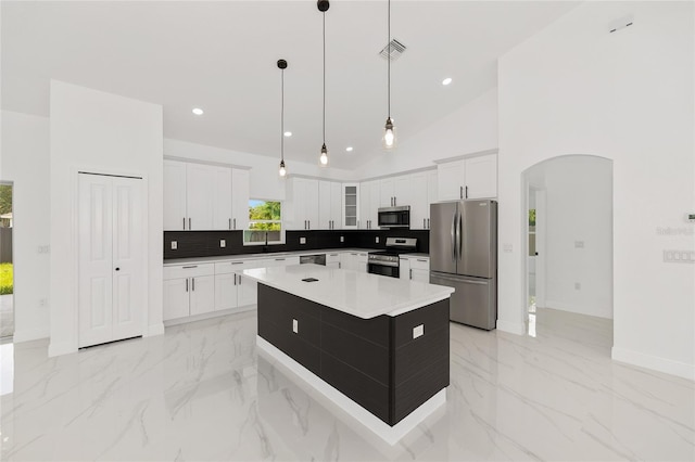 8456 SE 164th Pl, Summerfield, FL 34491 - kitchen with appliances with stainless steel finishes, arched walkways, baseboards, a kitchen island, and decorative backsplash