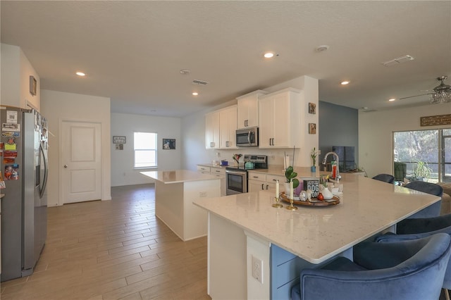 19551 SW 77th Loop, Dunnellon, FL 34432 - kitchen featuring appliances with stainless steel finishes, a center island, light wood finished floors, a peninsula, and white cabinetry