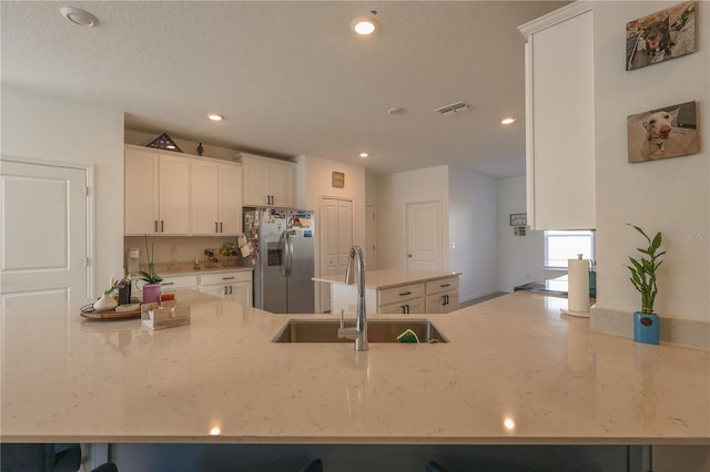 19551 SW 77th Loop, Dunnellon, FL 34432 - kitchen featuring stainless steel fridge with ice dispenser, a sink, white cabinetry, light stone counters, and recessed lighting