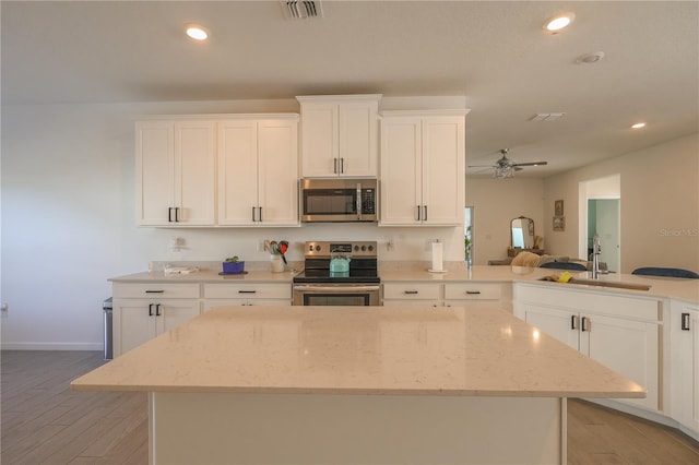 19551 SW 77th Loop, Dunnellon, FL 34432 - kitchen featuring appliances with stainless steel finishes, light wood-type flooring, a sink, white cabinetry, and recessed lighting