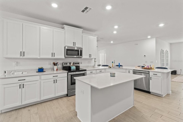 19551 SW 77th Loop, Dunnellon, FL 34432 - kitchen featuring appliances with stainless steel finishes, a peninsula, white cabinets, light countertops, and light wood-type flooring