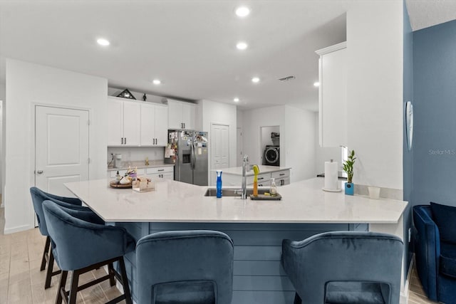 19551 SW 77th Loop, Dunnellon, FL 34432 - kitchen with stainless steel fridge with ice dispenser, washer / clothes dryer, white cabinets, recessed lighting, and a breakfast bar area