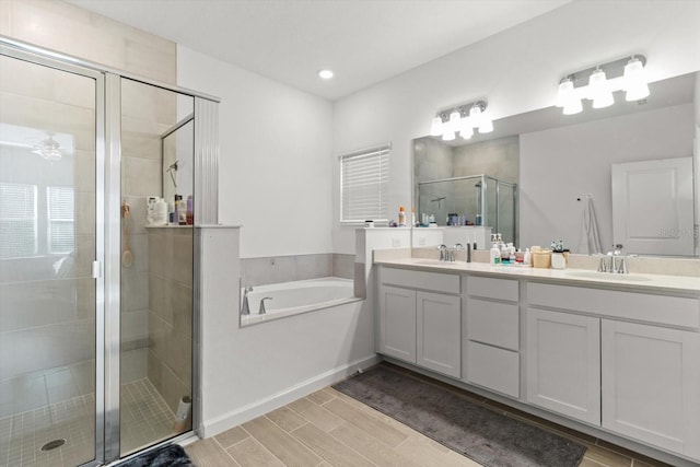 19551 SW 77th Loop, Dunnellon, FL 34432 - bathroom featuring a stall shower, double vanity, a bath, wood finish floors, and recessed lighting