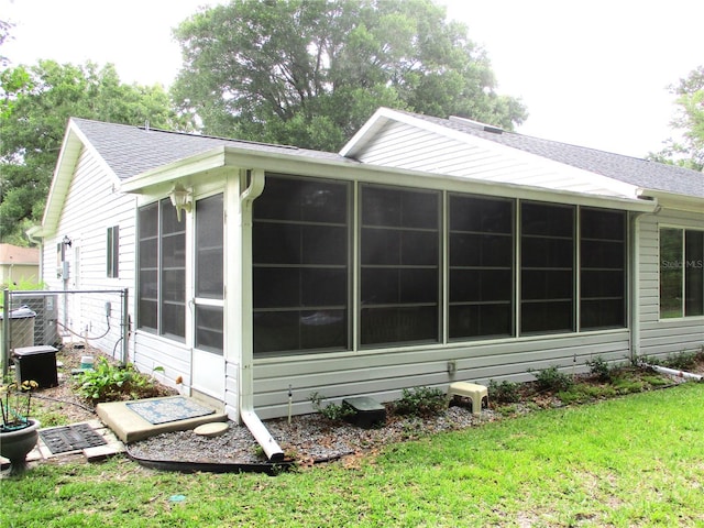 14192 SW 112th Cir, Dunnellon, FL 34432 - view of side of home with a sunroom, a shingled roof, and a lawn