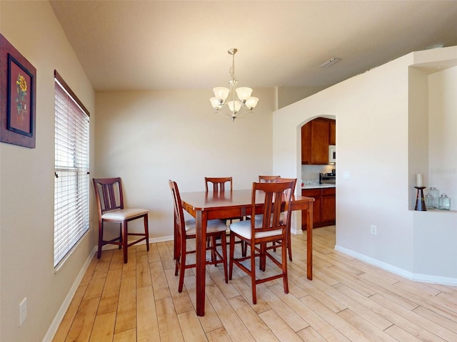 8080 N Susan Ave, Dunnellon, FL 34433 - dining space with arched walkways, light wood-type flooring, a chandelier, and healthy amount of natural light