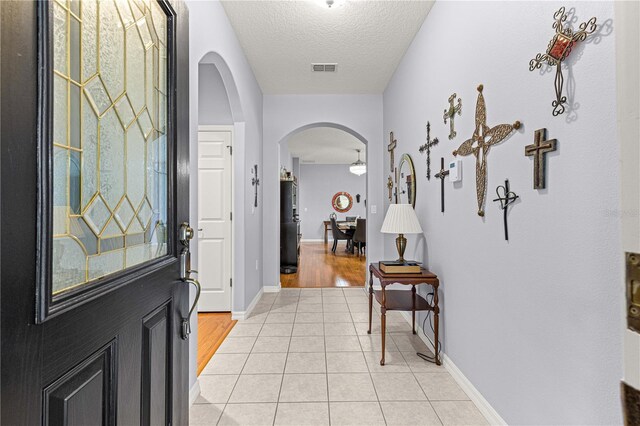 9551 SW 92nd Ter, Ocala, FL 34481 - foyer featuring arched walkways, light tile patterned floors, a textured ceiling, and baseboards