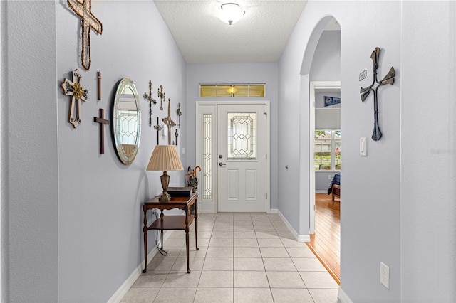 9551 SW 92nd Ter, Ocala, FL 34481 - foyer entrance with a textured ceiling, light tile patterned flooring, baseboards, and arched walkways