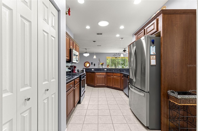 9551 SW 92nd Ter, Ocala, FL 34481 - kitchen with stainless steel appliances, light tile patterned floors, recessed lighting, brown cabinets, and decorative light fixtures