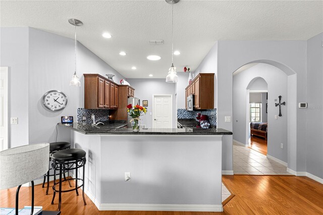 9551 SW 92nd Ter, Ocala, FL 34481 - kitchen featuring dark countertops, tasteful backsplash, appliances with stainless steel finishes, arched walkways, and a peninsula