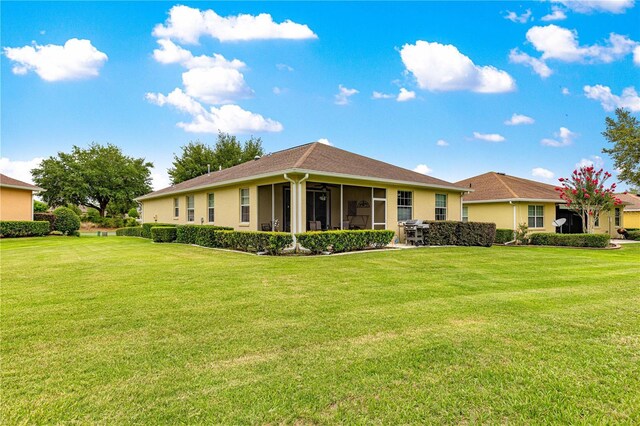 9551 SW 92nd Ter, Ocala, FL 34481 - rear view of property with a sunroom, a lawn, and stucco siding