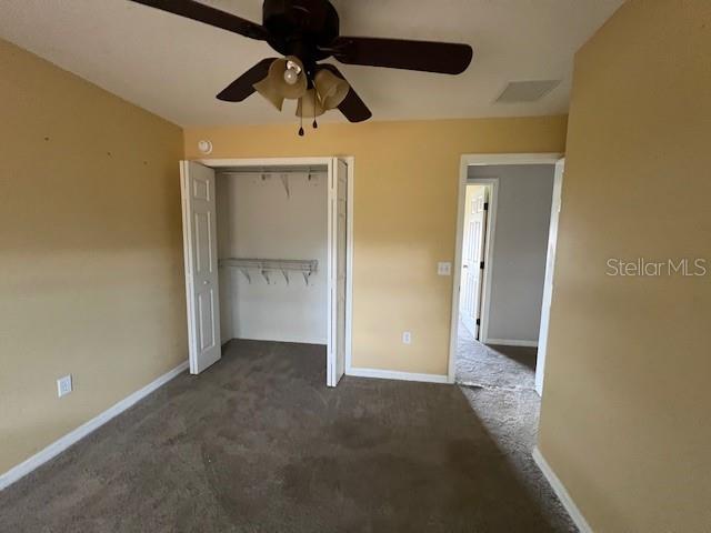8100 SW 56th Ter, Ocala, FL 34476 - unfurnished bedroom with a closet, dark carpet, baseboards, and a ceiling fan