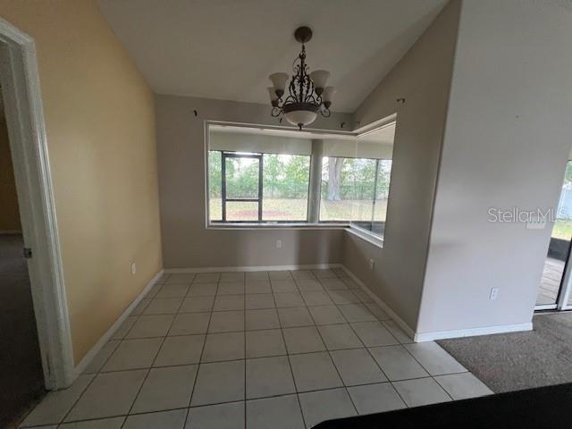 8100 SW 56th Ter, Ocala, FL 34476 - unfurnished dining area with vaulted ceiling, a chandelier, light tile patterned floors, and baseboards