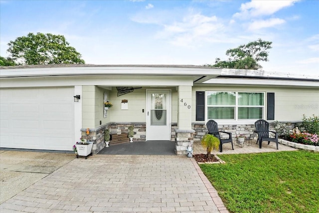 460 E Haines Blvd, Lake Alfred, FL 33850 - ranch-style home featuring solar panels, a garage, decorative driveway, and stone siding
