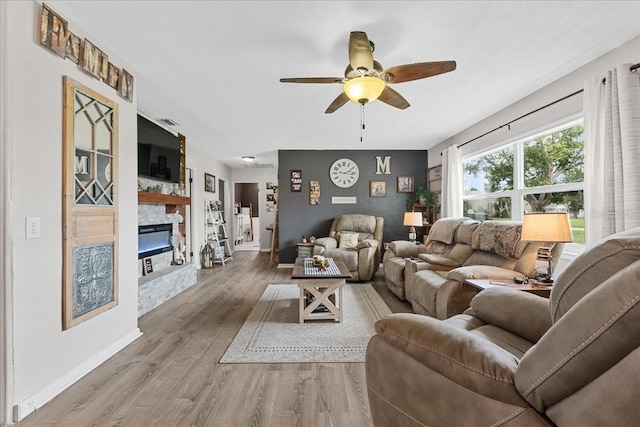 460 E Haines Blvd, Lake Alfred, FL 33850 - living area with a stone fireplace, a ceiling fan, wood finished floors, baseboards, and an accent wall