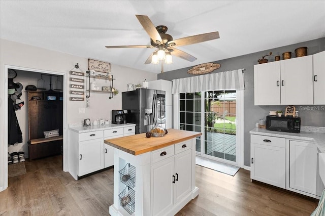 460 E Haines Blvd, Lake Alfred, FL 33850 - kitchen featuring stainless steel fridge, black microwave, wooden counters, white cabinets, and wood finished floors