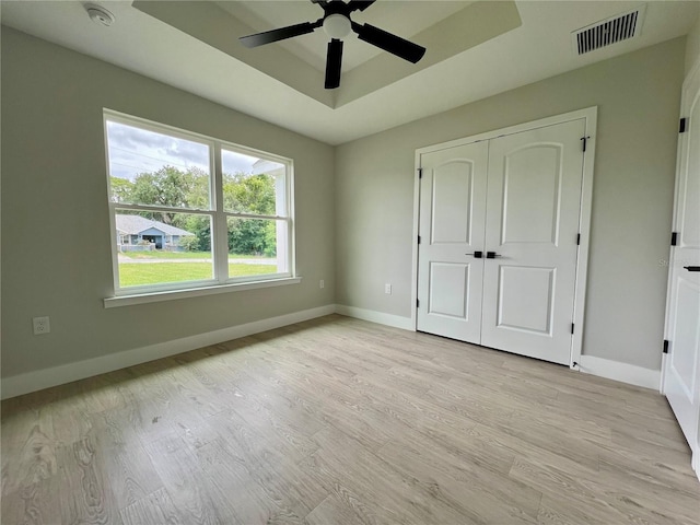 8289 SE 159th Ln, Summerfield, FL 34491 - unfurnished bedroom featuring a raised ceiling, light wood-style floors, a closet, and a ceiling fan