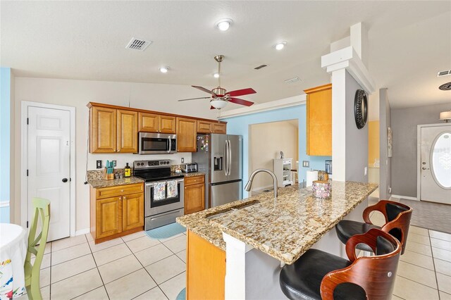 63 Walnut Crse, Ocala, FL 34480 - kitchen featuring stainless steel appliances, light tile patterned flooring, ceiling fan, a peninsula, and brown cabinetry