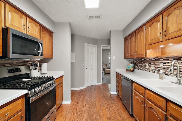 986 SE 57th Ave, Ocala, FL 34480 - kitchen with stainless steel appliances, light wood finished floors, backsplash, brown cabinetry, and a textured ceiling