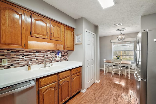 986 SE 57th Ave, Ocala, FL 34480 - kitchen featuring stainless steel appliances, light wood-style floors, brown cabinets, a sink, and a textured ceiling