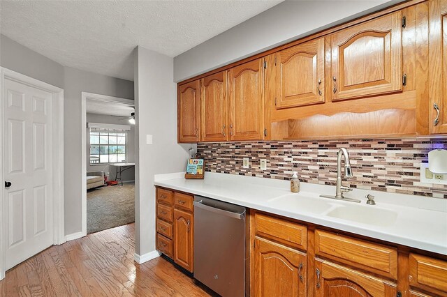 986 SE 57th Ave, Ocala, FL 34480 - kitchen featuring dishwasher, a sink, brown cabinetry, light wood-style flooring, and tasteful backsplash