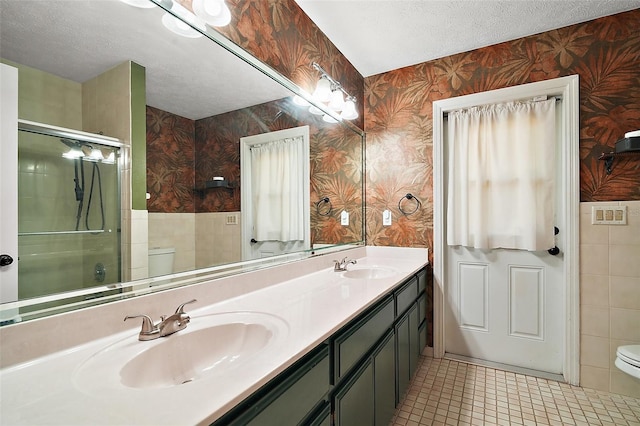 986 SE 57th Ave, Ocala, FL 34480 - bathroom with toilet, wallpapered walls, a textured ceiling, a shower with door, and double vanity