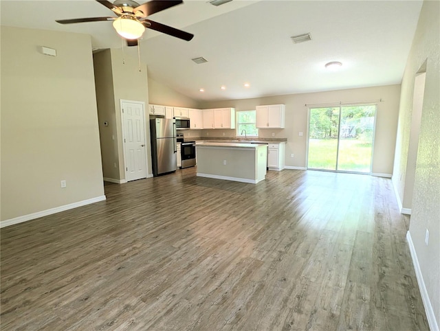 13921 SW 108th Ln, Dunnellon, FL 34432 - kitchen featuring stainless steel appliances, open floor plan, white cabinets, wood finished floors, and vaulted ceiling