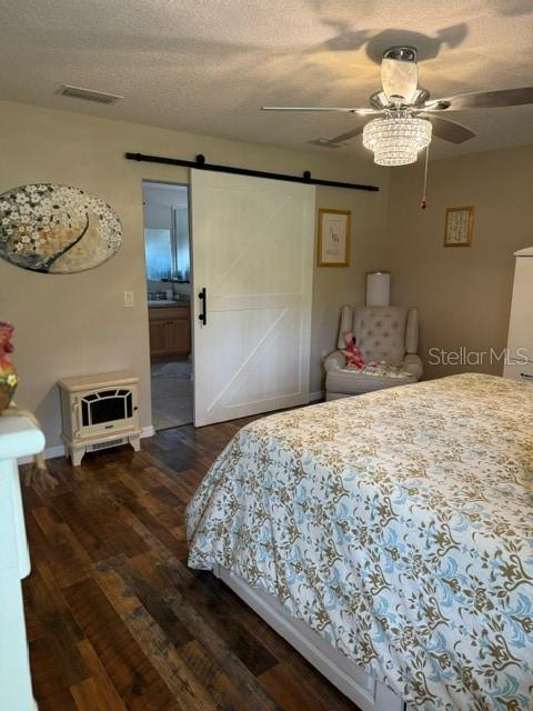 16023 SW 14th Avenue Rd, Ocala, FL 34473 - bedroom featuring a barn door, dark wood-style flooring, baseboards, a textured ceiling, and ceiling fan