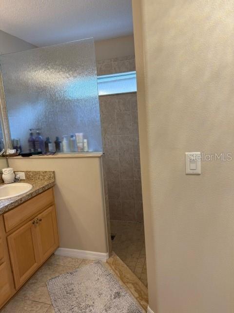 16023 SW 14th Avenue Rd, Ocala, FL 34473 - bathroom featuring vanity, walk in shower, tile patterned floors, and baseboards