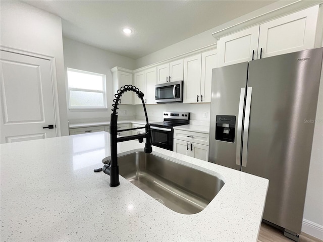 142 Guava Pass, Ocklawaha, FL 32179 - kitchen with appliances with stainless steel finishes, white cabinetry, light stone countertops, recessed lighting, and a sink